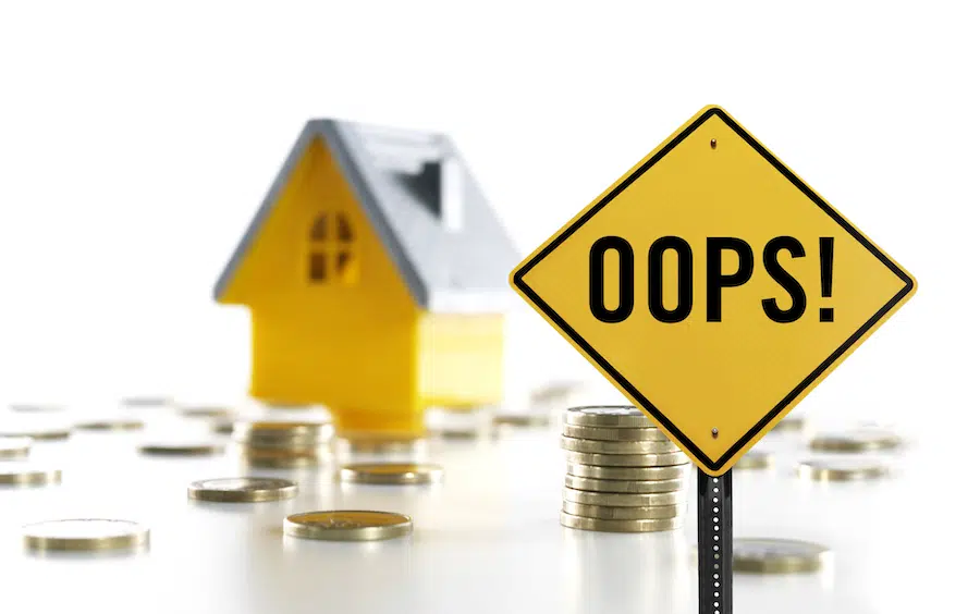 Traffic sign with "OOPS!" on it and tiny house in background surrounded by coins. Superior Heating Cooling Plumbing blog image.